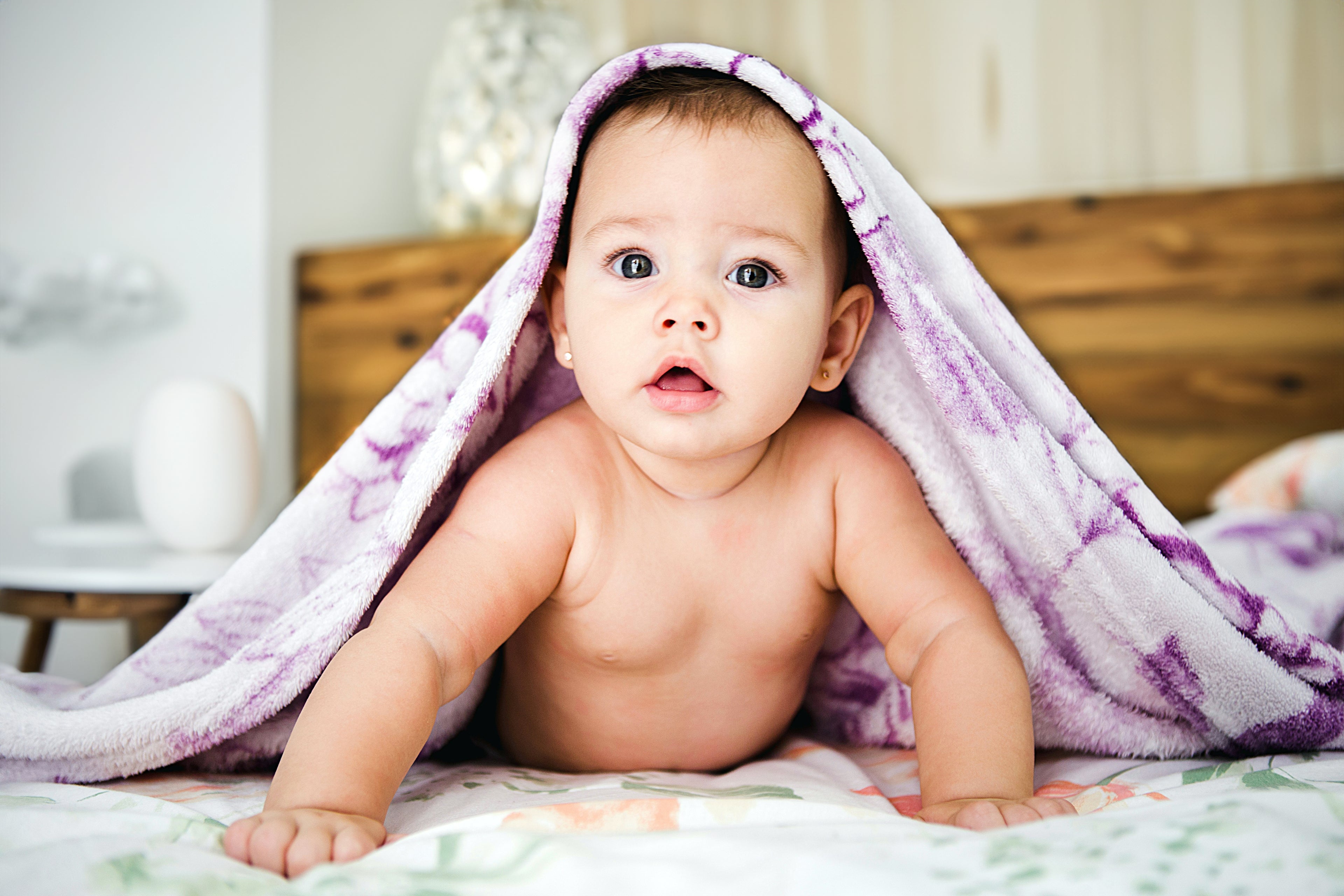Infant baby lying on a bed enjoying interactive playtime activities