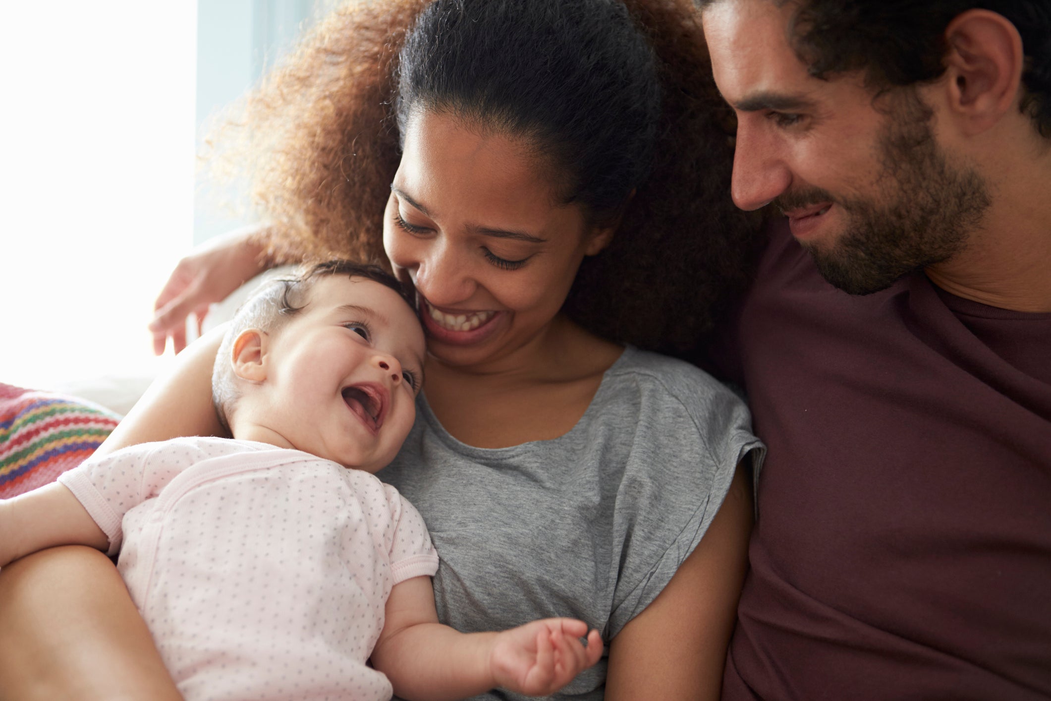 A mother and Father sitting with their baby bonding and smiling